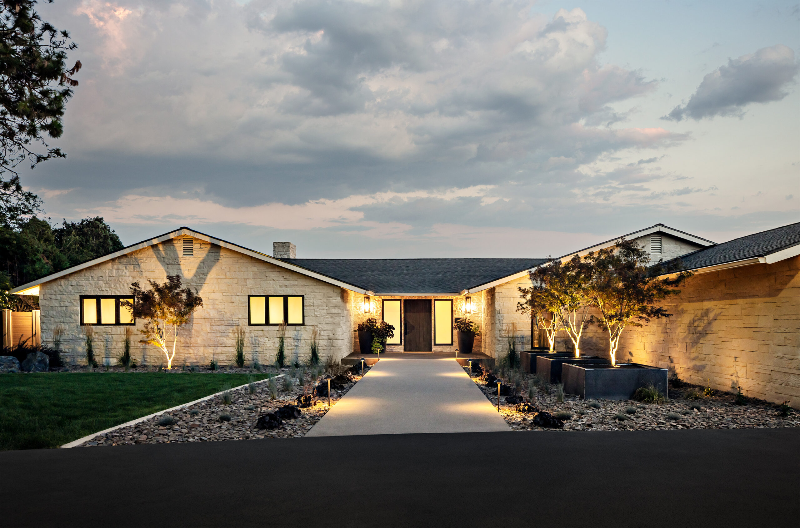 Modern home entrance with illuminated pathway and stone facade